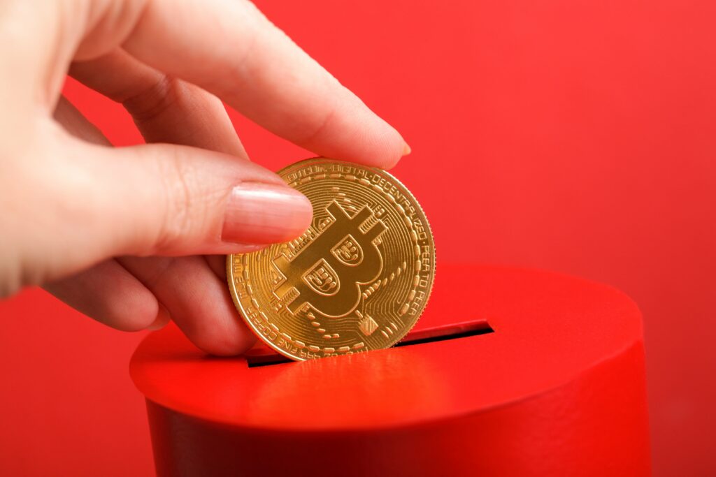 hand putting bitcoin into piggybank
