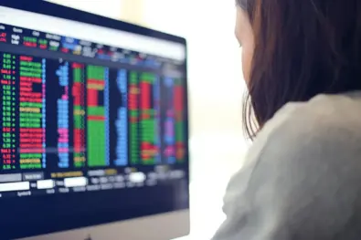 A woman, who is a trader, staring at the screen filled with indicators as she plans to make trading decisions.
